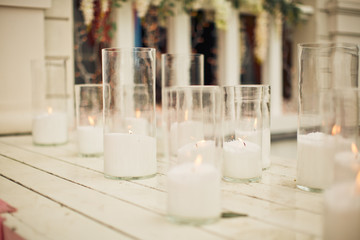 White candles in glass vases stand on white wooden porch