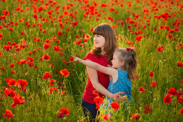 Naklejka na ściany i meble Mother and daughter smiling in a poppy field. The Picnic in the poppy field. Walk with family in poppy field. The cart poppies