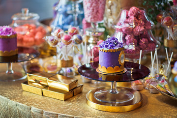 Violet cake with golden icing stands on the glass plate