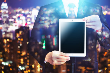 Business man holding tablet on blurry background.