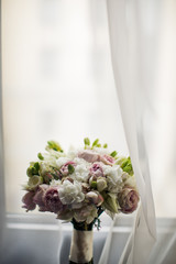 Rich wedding bouquet stands on the windowsill on white curtain