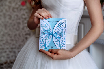 Wedding invitation blue card in the hands of the bride
