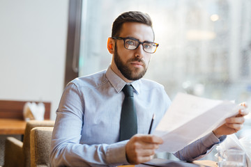 Businessman with papers waiting for partner in cafe