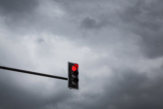 Red traffic light on a backdrop full of rain clouds