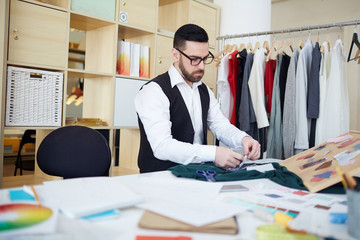 Young man working with fabric samples in atelier