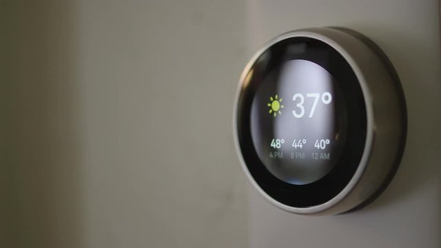 Woman Adjusting Smart Thermostat Gadget At Home