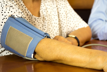Checking old woman patient arterial blood pressure