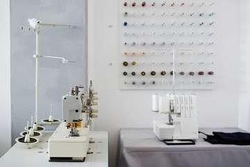 Background image of empty tailoring studio and tables with sewing machine and serger on it