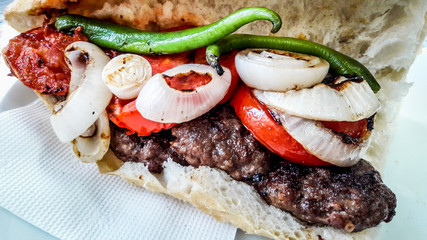Turkish Kofte Ekmek / Meatball Sandwich with tomatoes, onion and green pepper.