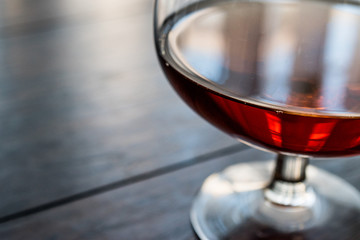 Glass of Cognac on wooden surface.