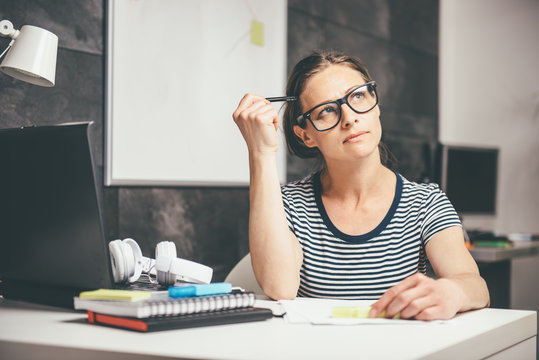 Woman writing notes and contemplating at the office
