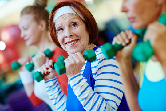 Healthy senior woman with dumbbells practicing physical exercise