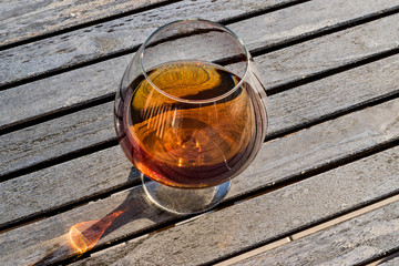 Glass of Cognac on wooden surface at garden (natural light)
