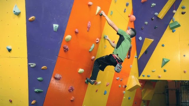 Young Climber Man Climbing Up On Practice Wall In Gym