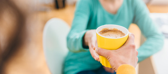 Woman giving coffee cup to her colleague