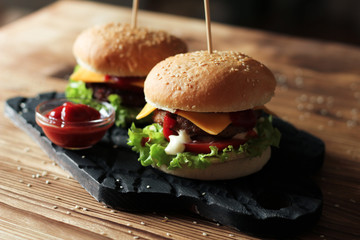 Two handmade burgers with beef, salad and cheese on wooden table.