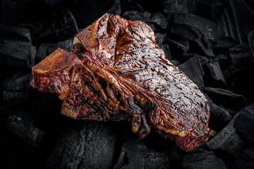 Grilling a tasty tender marinated t-bone steak on a coals.