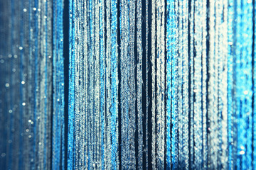 Background texture curtains made of blue threads with glitter and blur at the edges.