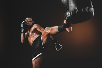 Fototapeta na wymiar focused muay thai fighter training with punching bag, action sport concept