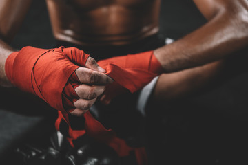 partial view of muay thai fighter swathign hand in boxing bandage