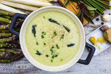 Delicious creamy asparagus soup on a wooden background.