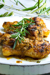Knusprige chicken drumsticks mit Rosmarin auf einer weißen Holzplatte
