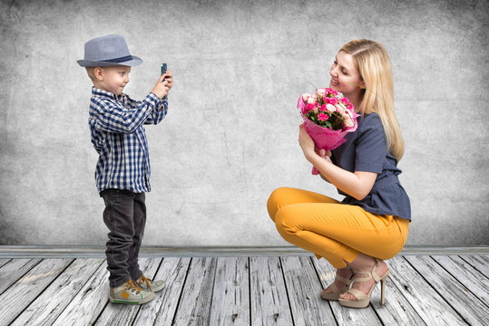 Little boy taking pictures on a mobile phone your mom with a bouquet of roses.Spring, concept of family vacation. Women's day,mother's day.