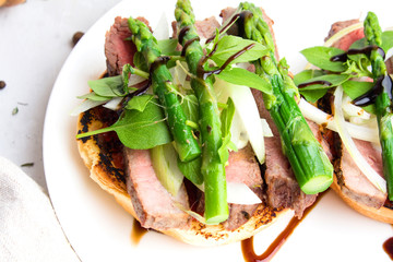 Burgers with roast beef and asparagus on white background closeup.