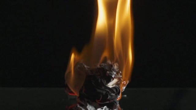 Timelapse. Fire, the process of burning paper, smoke, black background. Close-up.

