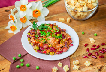 Homemade Stewed beans with chicken meat green peas and vegetables served with cut green onion and parsley on a white plate and croutons on wooden table