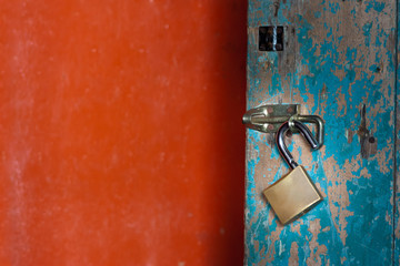 Vintage (retro) metal lock on a wooden door. Classic hanging lock. Attrition, old paint and dirt. Soft focus.