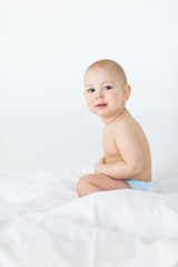 adorable baby boy sitting on bed  isolated on white, 1 year old baby concept