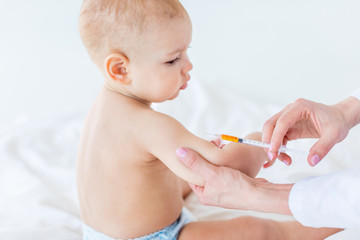 Cropped shot of medical worker making injection for cute baby boy, 1 year old baby concept