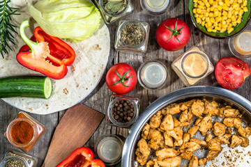 Preparing of doner kebab with gyros meat, chicken stripes fried on pan and vegetable ingredients, homemade cooking recipe, flat lay, overhead