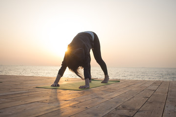Young woman doing yoga in the beach. Morning sea background. 