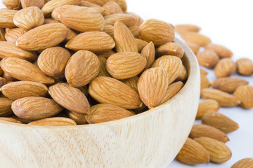 Almond in wooden bowl on white background isolated.