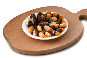 Slices of tangerine in chocolate on wooden cutting board
