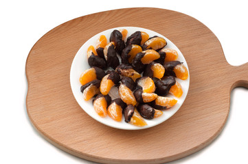 Slices of tangerine in chocolate on wooden cutting board