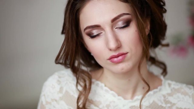 Girl with make-up in a wedding dress sits in a beautiful room