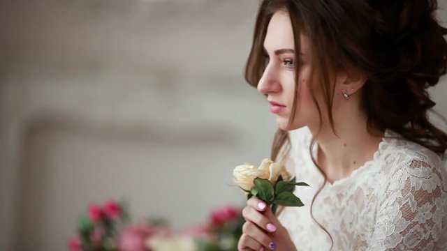Girl with make-up in a wedding dress sits in a beautiful room