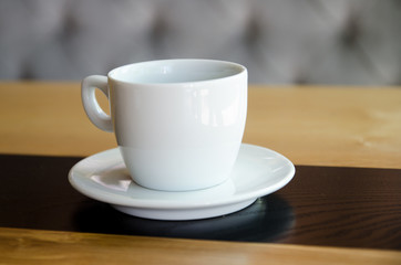A cup of black coffee in a white cup on wooden background. 