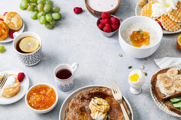 Morning atmosphere. Healthy breakfast with porridge, oatmeal, pancakes, lots of berries and snacks on blue rustic background. Text space at the center.