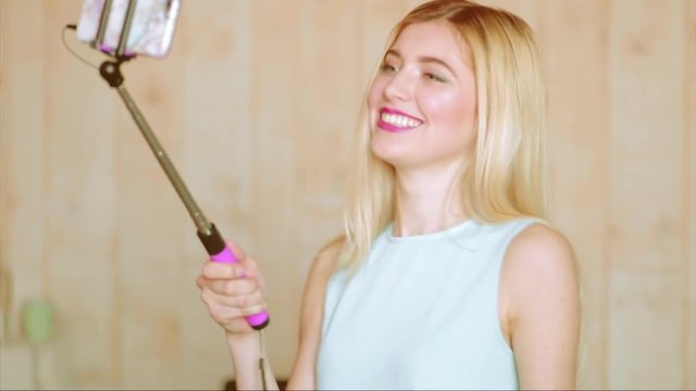 Attractive blonde woman, technology and leisure concept - happy female taking selfie on smartphone at home