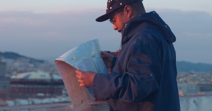 black african american traveler looks at the map in city background panorama