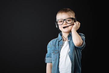 Positive little boy wearing headphones with microphone