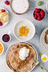 Morning atmosphere. Healthy breakfast with porridge, oatmeal, pancakes, lots of berries and snacks on blue rustic background.