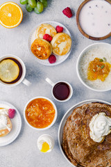 Morning atmosphere. Healthy breakfast with porridge, oatmeal, pancakes, lots of berries and snacks on blue rustic background.