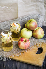 Apple cider with slices of apples in transparent glasses on a wooden board