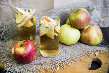 Apple cider with slices of apples in transparent glasses on a wooden board