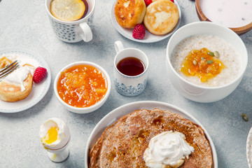 Morning atmosphere. Healthy breakfast with porridge, oatmeal, pancakes, lots of berries and snacks on blue rustic background.